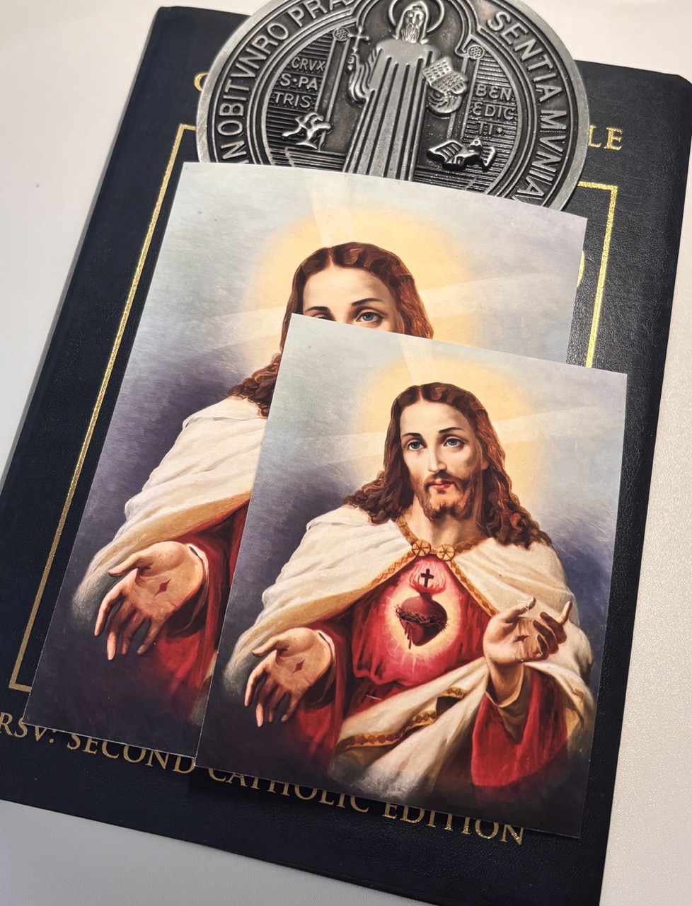 Religiöses Kunstwerk von Jesus mit dem Heiligen Herzen auf einer katholischen Bibel und Medaille, das Glauben und Hingabe symbolisiert. Sacraresponda